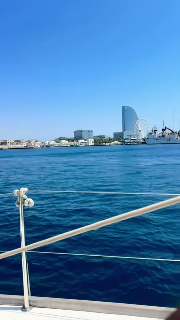 A sailing boat on the sea off Barcelona with the city skyline behind
